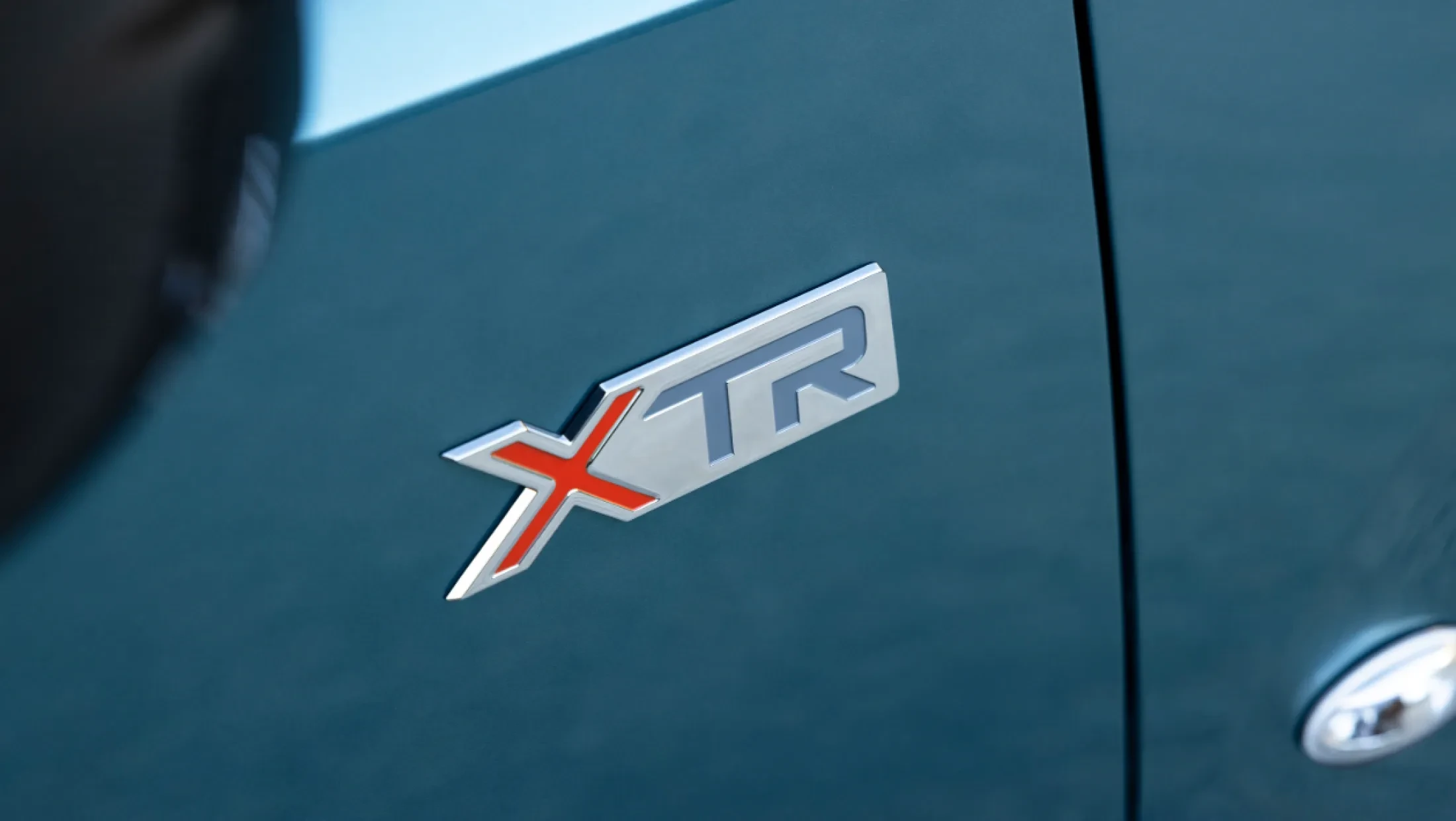 Zijaanzicht van de Citroën Berlingo XTR, geparkeerd buiten, met het XTR-logo zichtbaar op de carrosserie en de typische styling van het model.