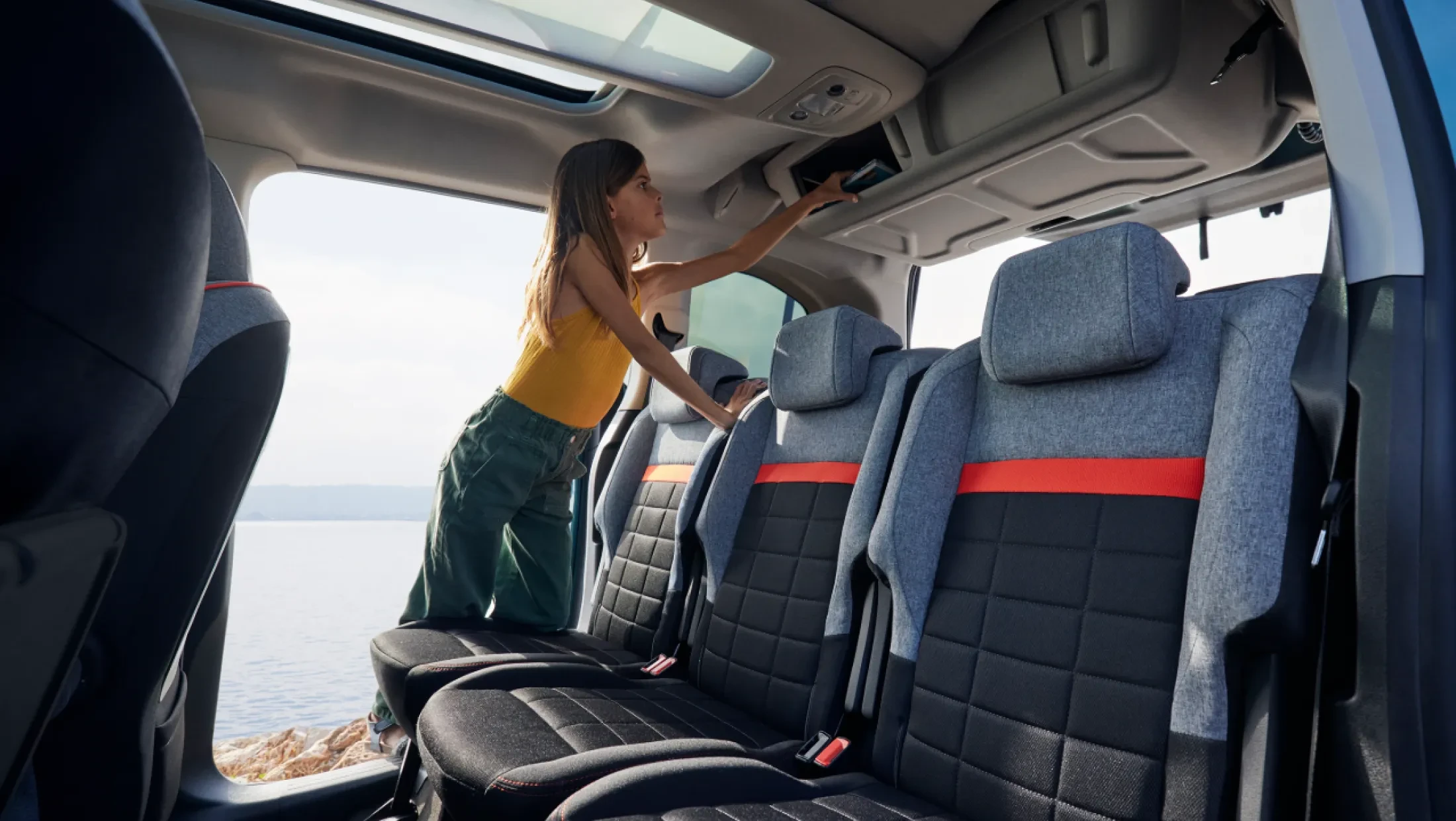 Achterinterieur van de Citroën Berlingo, met zicht op de tweede rij stoelen, ruime beenruimte en opbergvakken, geschikt voor passagiers of bagage
