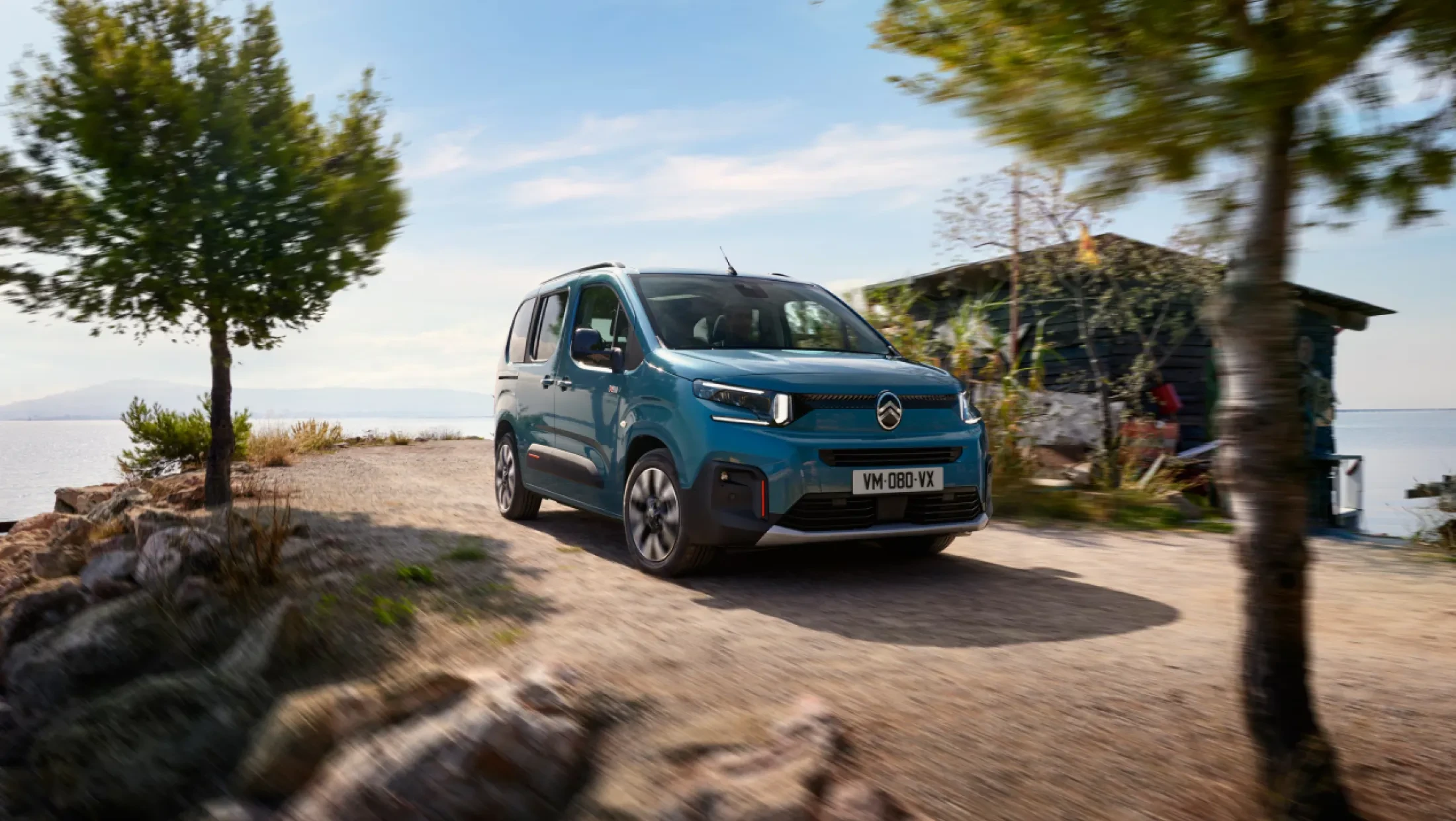 Zijaanzicht van de Citroën Berlingo, geparkeerd op straat, met zicht op de portieren, ramen en wielen.